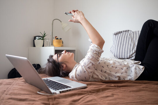 Portrait of a young female model laying on the bed and using laptop