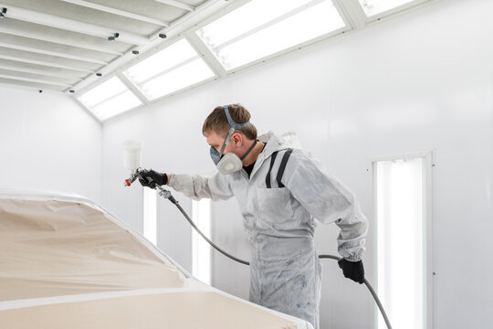 Technician painting vehicle in modern garage