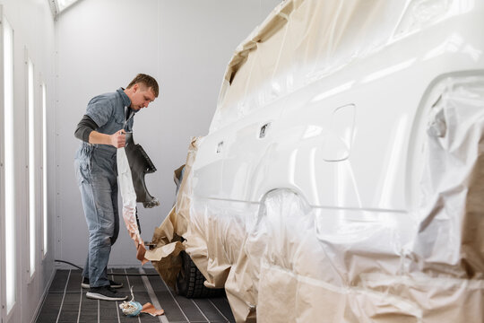 Male worker removing part from car