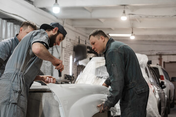 Male mechanics working with painted car detail