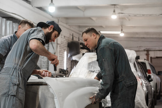 Male mechanics working with painted car detail