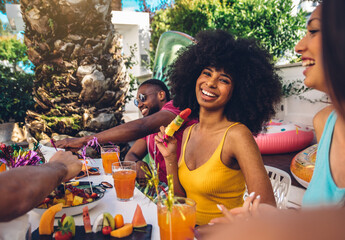 Group friends having fun drinking cocktails sitting in villa backyard - Happy young hispanic woman...