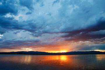 Naklejka na ściany i meble Dramatic clouds over the lake. Sunset. Storm.