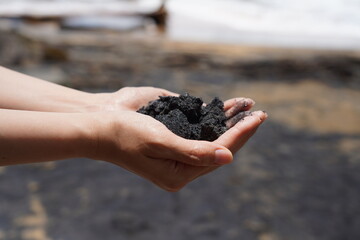 Fine black sand from the unseen black sand beach travel location in Thailand. It is holding on people hand. Natural object close-up photo.