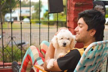 young man hugging smiling his poodle dog