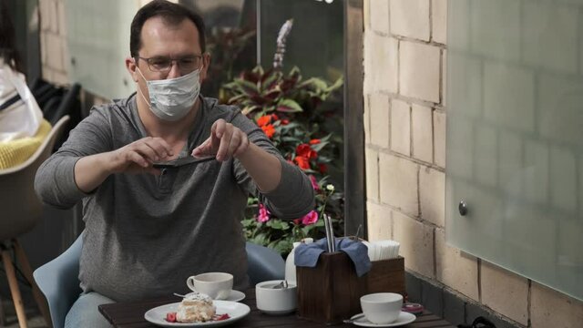 Man have couh in medical mask doing food photo on a mobile phone during a pandemic