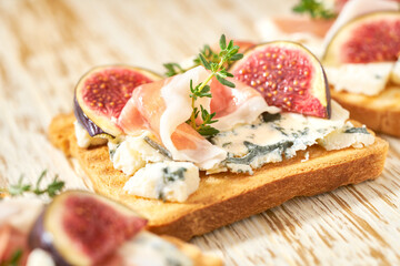 Delicious toast with figs, blue cheese, jamon and thyme close-up.