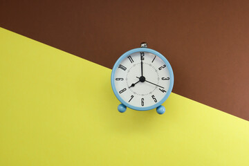 Fototapeta na wymiar Alarm clock on yellow and brown background 