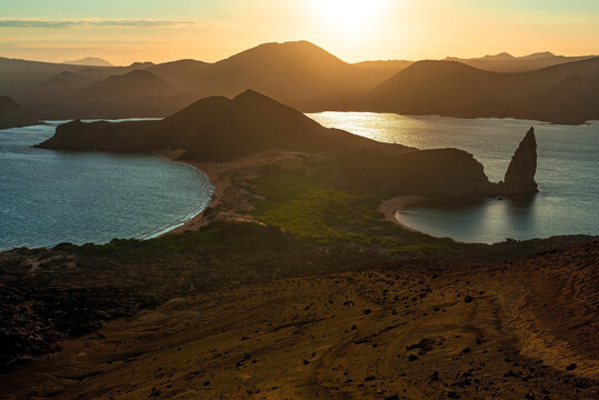 Bartolome island with Pinnacle Rock at sunset with Santiago island in the background, Galapagos national park, Ecuador.