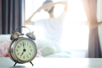 Morning of a new day, alarm clock wake up woman sitting in the room. A woman stretch the muscles at...