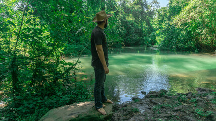 Man standing in front of a beautiful river with a green color water in Honduras
