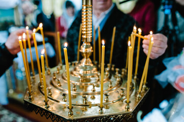 The hand people lights a candle near the candlestick in the church.