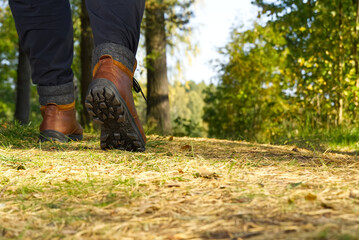 Man hiking in the woods in Autumn pine forest. Men boots walking in the woods on sunny day. hiking concept, outdoor lifestyle.