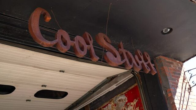 This panning video shows a vintage metal sign that says "cool stuff" with an arrow pointing downwards.