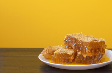 Honeycombs in white plate on the wooden table. Natural organic bee product. Healthy lifestyle. Copy space for your text. Close-up photo.