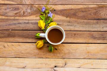 Fototapeta na wymiar hot coffee with yellow flowers ylang ylang of lifestyle arrangement flat lay postcard style on background wooden