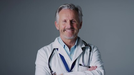 Studio portrait of mature male doctor wearing white coat against grey background - shot in slow motion - Powered by Adobe
