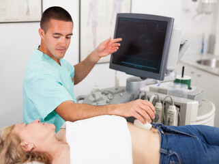 Man doctor examination a mature woman at abdomen with ultrasonography device