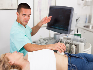 Obraz premium Man doctor examination a mature woman at abdomen with ultrasonography device