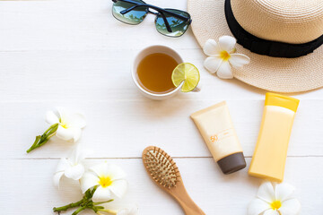 sunscreen spf50 cosmetics beauty makeup for skin face with body lotion, comb, hat, sunglasses and herbal drinks of lifestyle woman relax arrangement flat lay style on background white wooden