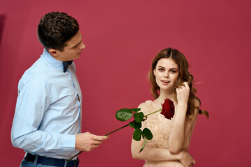 enamored man and woman with a red flower on a pink background hug each other Copy Space