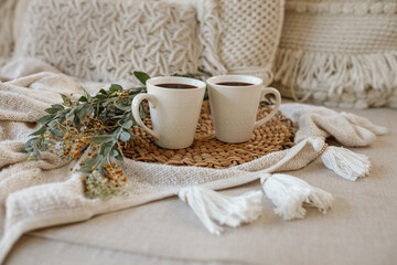 Two cups with coffee on wooden serving tray in the cozy bed with blanket. Knitting warm woolen sweater in the autumn weekend