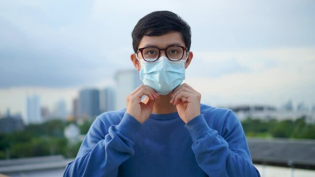 close up asian man wearing protective face mask at outdoor to protect coronavirus and pollution from environment for new normal behavior lifestyle concept