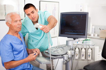 Obraz premium Portrait of young efficient positive sonographer showing new ultrasound scan to mature doctor in hospital