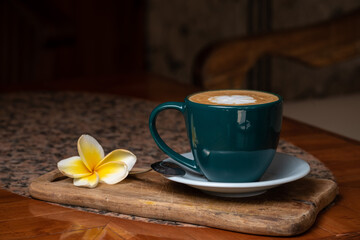 Coffee cup on stone kitchen table. Cappuccino, hot latte or coffee with milk cup on the white plate the wood board. Flower Frangipani. Healthy, vegan, vegetarian, almond milk