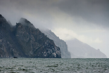 Fototapeta na wymiar Epic panorama of the Bering Sea coastline. View of the huge rocky capes. Nature of the far North of Russia and the Arctic. Eastern coast of Chukotka, Russian far East. Gloomy cloudy autumn weather.