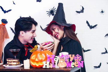 holiday and people concept - happy halloween. Dracula giving a gift to the witches girlfriend for eating at the party over black background