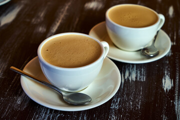 Two cups of coffee on a wooden table.