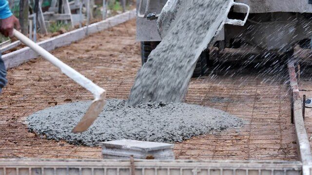 Pouring concrete mix on concreting formwork on road in construcktion site