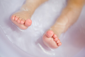 Toddler feet in detail on toes in a tub of water.