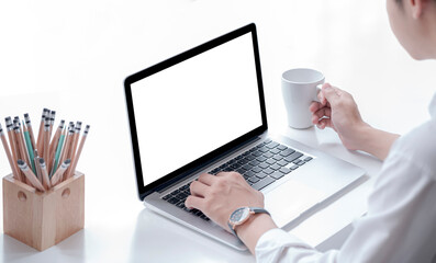 Closeup view of man hands working with laptop computer and holding mug while sitting at office desk.