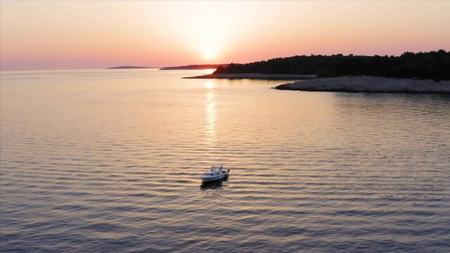 Aerial shot circling a boat at sunset off the coast of Losinj island, Croatia.