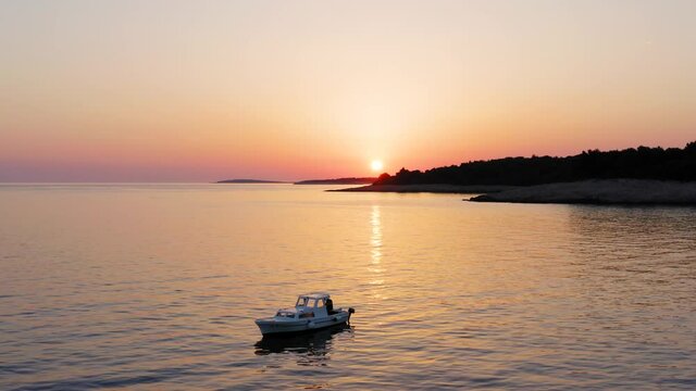 Mid-range aerial shot circling around a boat at sunset off the coast of Losinj, Croatia.