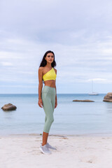 Attractive young  woman in colorful sport wear on beach.  