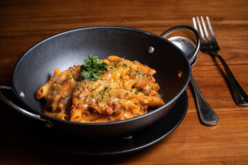 Pasta penne with spicy tomato sauce, parmesan and parsley. Tomato, olive oil, spices, herbs, cheese, tomato sauce on a wooden table.