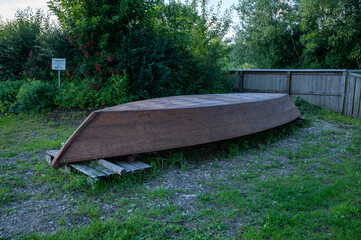 a wooden boat lies upside down on poles on a meadow