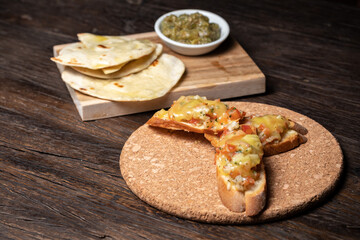 Bruschetta with half dried tomatoes and cheese. Middle Eastern meze with pita, olives, colorful hummus, babaganush, pickles, vegetables. Healthy food, vegan vegetable dish. tacos and snack wood table