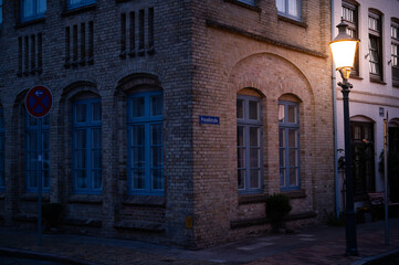Fototapeta na wymiar street lamp shines at an ahistoric house in the dutch town of friedrichstadt in northern germany