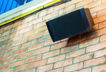 Old-fashioned speakers mounted on a brick wall in a restaurant to play music for diners. Real...