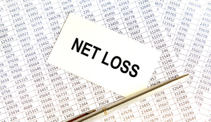 In the background of the report, there is a card with the inscription NET LOSS, next to a silver pen.