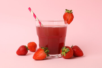 Glass with fresh strawberry juice on pink background