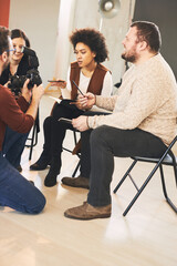 Small group of attendees sitting in photography studio and asking questions about camera parts.