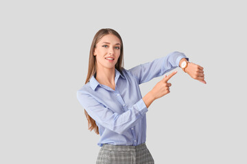 Young woman with wristwatch on light background