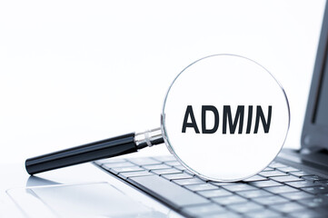 Admin inscription on a magnifying glass lying on the laptop keyboard