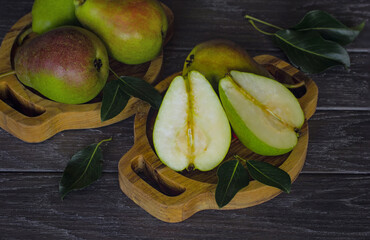 ripe green pears in wooden bowls on the table close-up. background with pears, pear halves and green leaves.