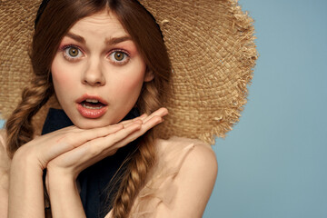 Girl in a straw hat portrait close-up pigtails fun red hair blue background